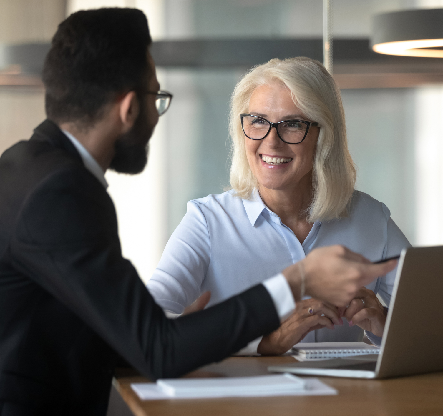 Businessman consulting mature businesswoman client, using laptop